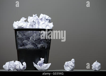 Cestino riempito con carta accartocciata. Sfondo grigio Foto Stock