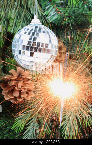 La masterizzazione (lit) sparkler nella parte anteriore dell'albero di Natale. Foto Stock