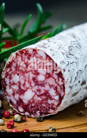 Salame peper calli rosmarino sul bordo di taglio Foto Stock