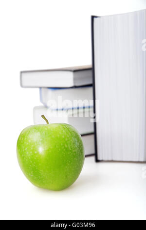 Bright green apple e libri su uno sfondo Foto Stock