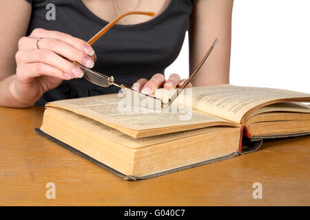 Le mani della ragazza con gli occhiali sopra il libro aperto isolato Foto Stock