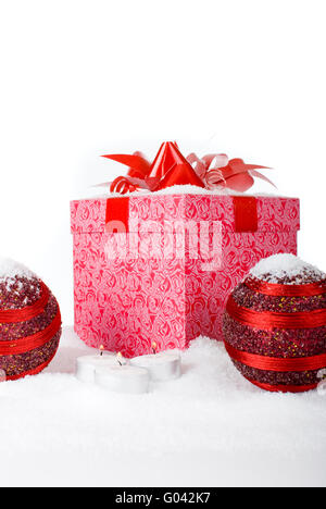 Regalo di natale Scatola nella neve con palline rosse e candele Foto Stock