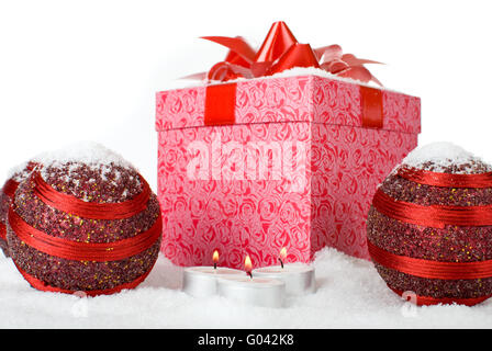 Regalo di natale Scatola nella neve con palline rosse e candele Foto Stock