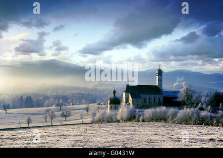 Bellissimo il pupazzo di neve in mattinata il paesaggio alpino con chiesa pictursque Foto Stock