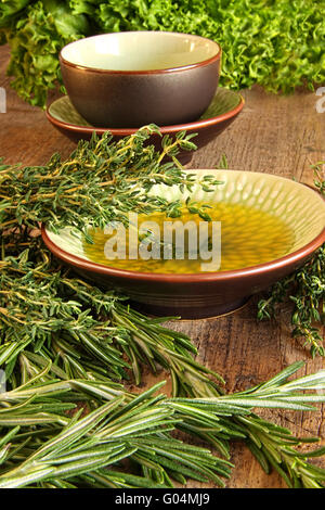 Le erbe fresche con olio d'oliva sul tagliere di legno Foto Stock