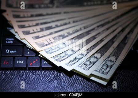 Business online di concetto. Dollari USA banconote sulla tastiera del notebook Foto Stock