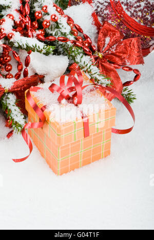 Albero di natale nella neve con palline rosse e confezione regalo Foto Stock