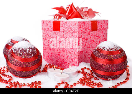 Regalo di natale Scatola nella neve con palline rosse e candele Foto Stock