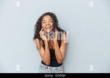 Ridendo afro american donna parlando al telefono su sfondo grigio Foto Stock