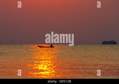 La barca con il pescatore in mare su uno sfondo di tramonto Foto Stock