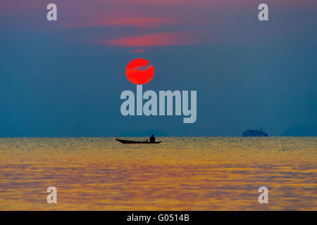 La barca con il pescatore in mare su uno sfondo di tramonto Foto Stock