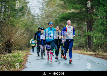 Un gruppo di ragazze giovani atleti lungo la strada durante la mezza maratona nel bosco Foto Stock