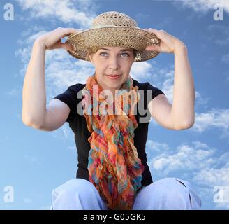 Una donna in un cappello su uno sfondo cielo guarda lontano Foto Stock