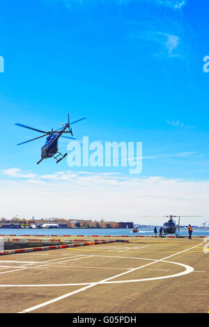 New York, Stati Uniti d'America - 25 Aprile 2015: nero elicotteri in Lower Manhattan a New York, Stati Uniti d'America, su East River. Pier 6. East River e grattacieli di Brooklyn sullo sfondo. La gente sul pad. Foto Stock