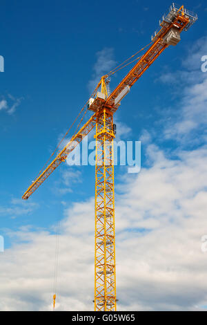 Tall white tower crane contro il blu intenso del cielo. Foto Stock