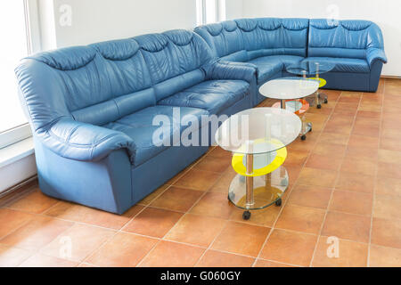 Svuotare il salotto con un grande divano blu e due piccoli tavoli. Foto Stock