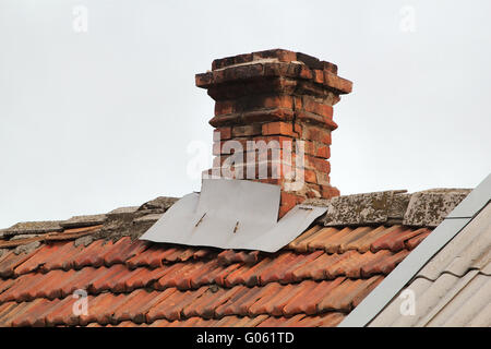 Vecchia tubazione dal forno sul tetto fuori le assicelle, sul cielo grigio sfondo Foto Stock