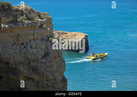 Imbarcazione turistica visitando le scogliere e le grotte vicino Albandeira beach, un'attrazione popolare fra i turisti durante la stagione estiva Foto Stock