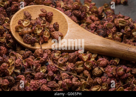 Cucchiaio di legno in grani di pepe Szechuan ardesia sul bordo di taglio Foto Stock