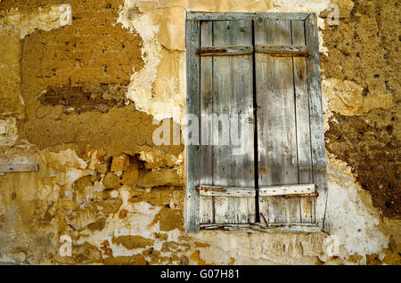 Parete di frammento della vecchia casa abbandonata con la finestra chiusa. Foto Stock