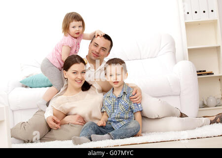 Famiglia giacente su un tappeto nel loro salotto Foto Stock