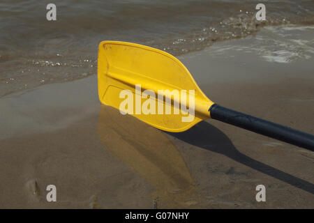 Giallo kayak paddle posa sulla sabbia bagnata riverbank Foto Stock