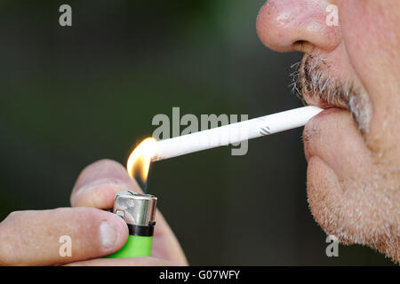 Fumare una sigaretta contro uno sfondo scuro Foto Stock