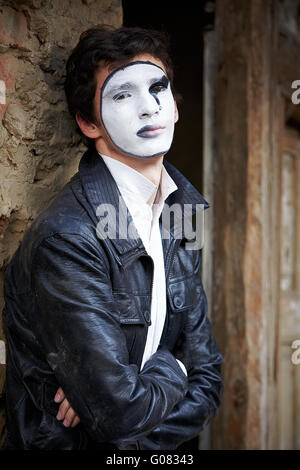 Guy mime contro un vecchio muro di mattoni. Foto Stock