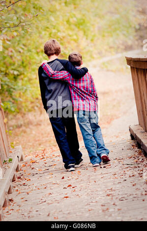 Due fratelli abbracciando e camminando sul ponte Foto Stock