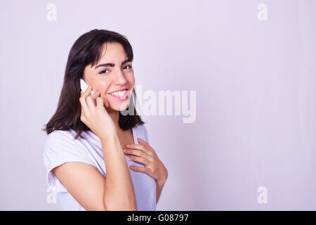 Ritratto di ispanici giovane donna utilizzando un telefono cellulare. Donna che parla al telefono, isolate su brackgroung grigio. Foto Stock