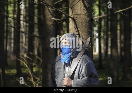 Uomo con un machete nei boschi addossato a t Foto Stock