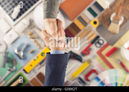 Imprenditori stringono le mani, costruzione e ristrutturazione di casa gli strumenti su sfondo, vista dall'alto Foto Stock