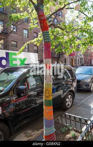 Albero sulla strada residenziale in Hell's Kitchen, New York, con un vivacemente colorato a maglia sul coperchio (filato bombardamento) CON I Love NY Foto Stock