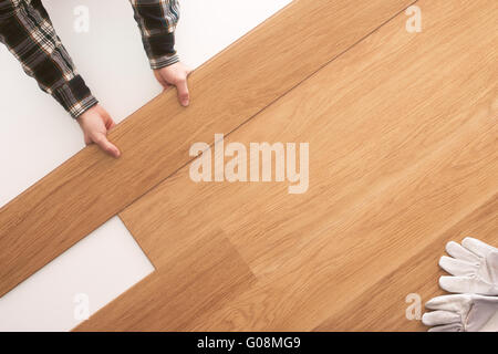 Qualità superiore con pavimento in legno installazione a casa, falegname ponendo le mani una piastrella sul pavimento vista superiore Foto Stock