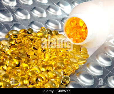 Liquido giallo capsule e piastre argenteo di medic Foto Stock