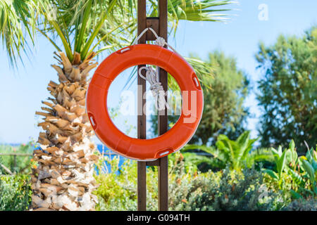 Orange salvagente con corda appesa intorno alla piscina Foto Stock