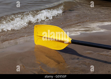 Giallo kayak paddle posa sulla sabbia bagnata riverbank Foto Stock