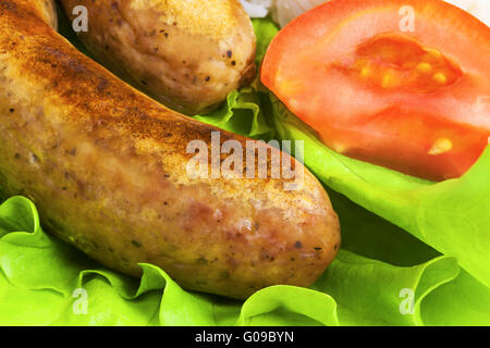 Salsicce fritte su foglie di lattuga Foto Stock