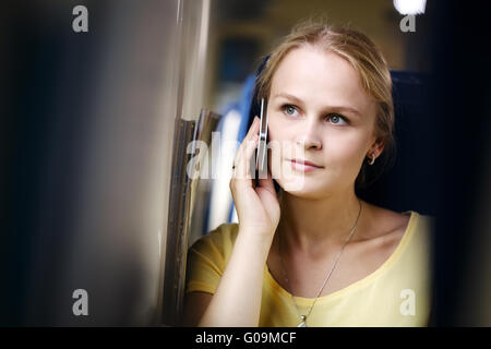 Donna attraente l'ascolto di una chiamata sul suo cellulare che viaggiano in treno Foto Stock