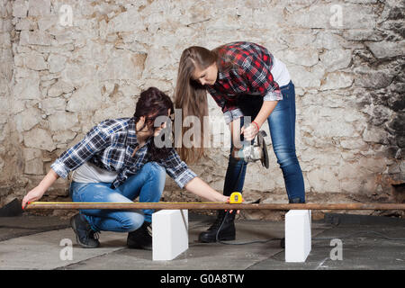 Due dai lunghi capelli donna giovane con una smerigliatrice angolare Foto Stock