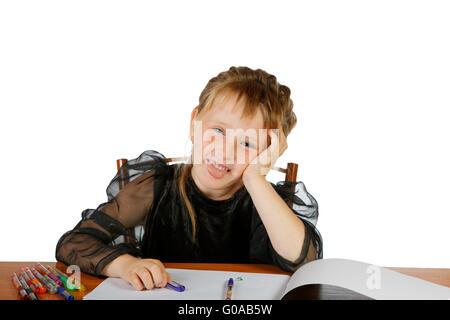 La ragazza si siede a un tavolo e mette fuori la lingua Foto Stock