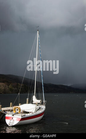 Yacht bianco contro un broody, Moody, buia e tempestosa cielo a Ullswater nel Lake District Cumbria nel nord dell'Inghilterra Foto Stock