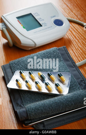 Compresse e il dispositivo per la misurazione della pressione su un tavolo Foto Stock