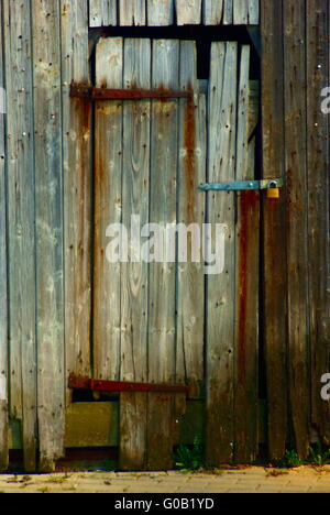 Stalla diroccata porta con un nuovo lucchetto Foto Stock