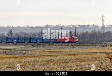 In treno con la rossa locomotiva elettrica e carro blu Foto Stock