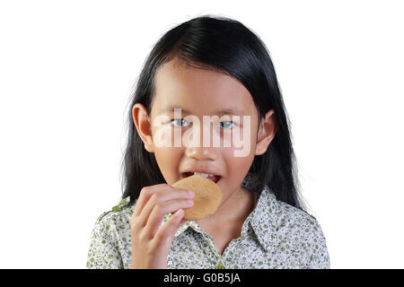 Ritratto di un piccolo felice ragazza asiatica sorridente mentre mangia il biscotto isolato su bianco Foto Stock