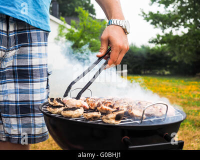 Lo Chef cottura alla brace con un sacco di fumo Foto Stock