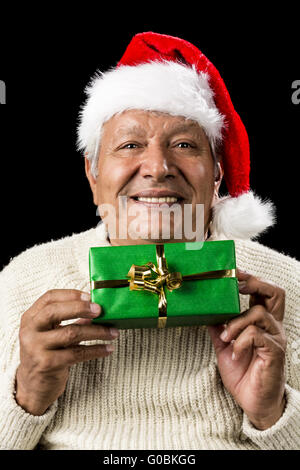 Sorridendo Il vecchio uomo di consegnare un avvolto verde regalo Foto Stock