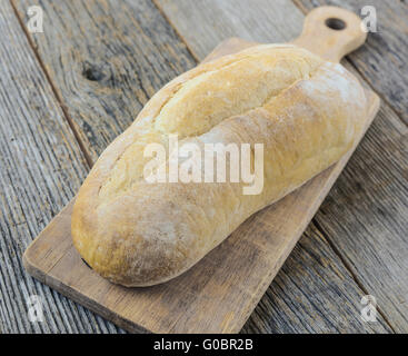 Il pane su una scheda di pane rustico con uno sfondo di legno Foto Stock