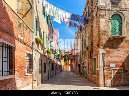 Biancheria e indumenti su funi tra vecchie case in mattoni in cortile tipico di Venezia, Italia. Foto Stock